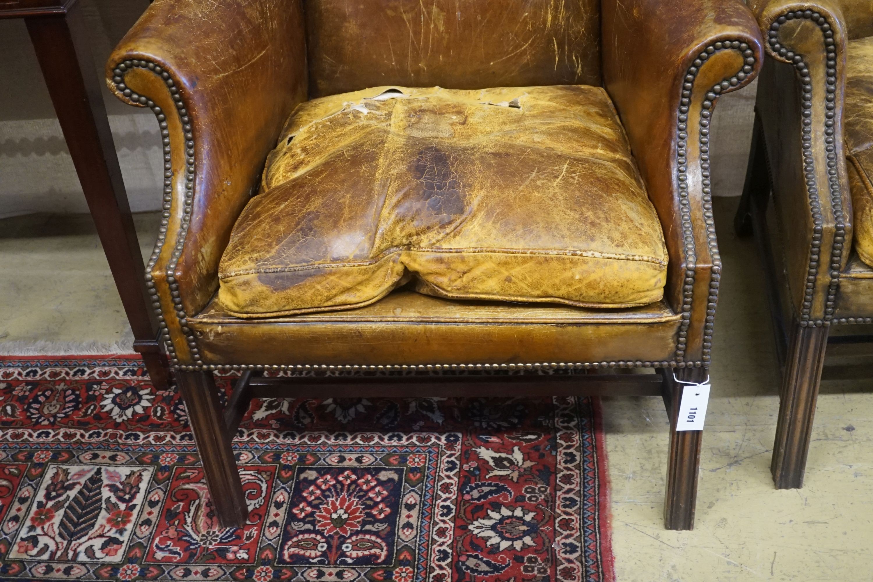 A pair of George III style tanned leather wing armchairs